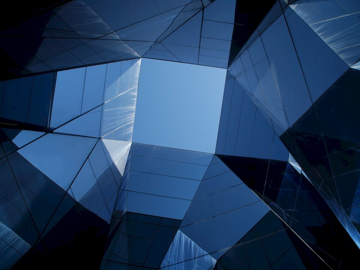 A view upwards through geometrically arranged glass and steel structures, creating a modern and abstract architectural design.