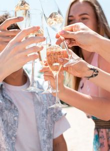 A group of people is celebrating, clinking champagne glasses together outdoors, suggesting a festive occasion or gathering.