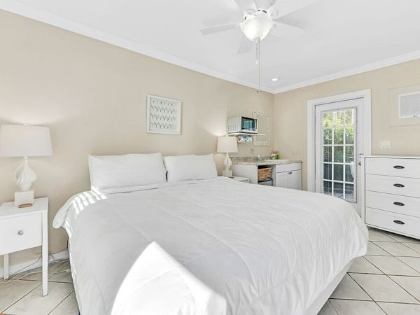 A cozy bedroom with a large bed, nightstands with lamps, a dresser, and a windowed door leading outside.