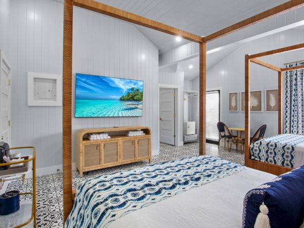 A cozy bedroom with a canopy bed, patterned floor, wall-mounted TV, and decorative accents creating a relaxing atmosphere.