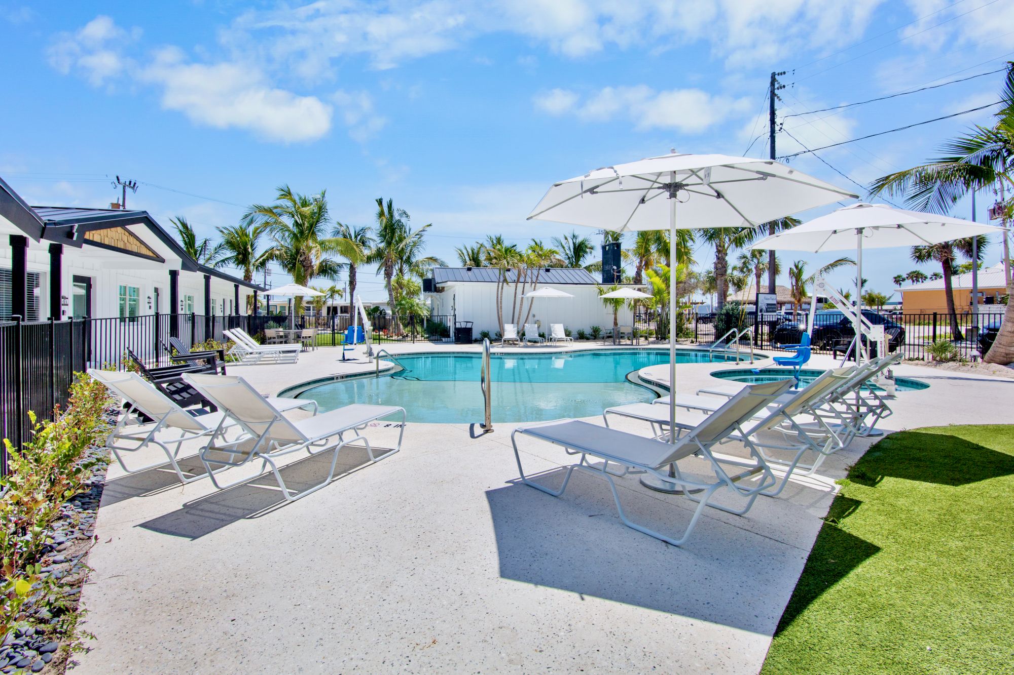 A sunny pool area with lounge chairs, umbrellas, and palm trees, perfect for relaxing and enjoying a tropical atmosphere.