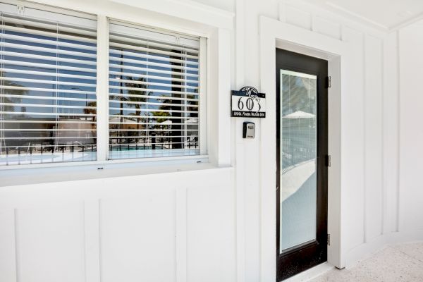The image shows a white exterior wall with a window, door, and a sign reading "609" near the door.