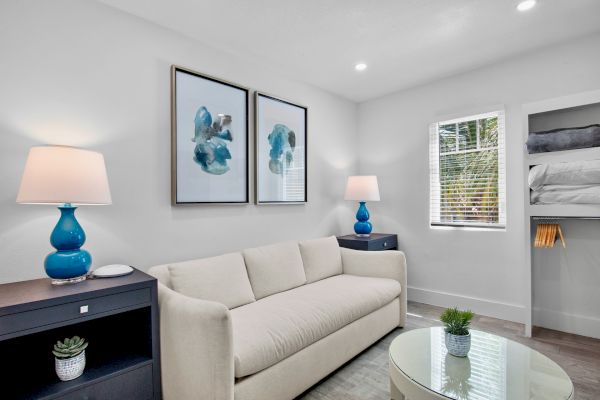 A modern living room with a beige sofa, blue lamps, abstract wall art, and minimal decor in a bright space.
