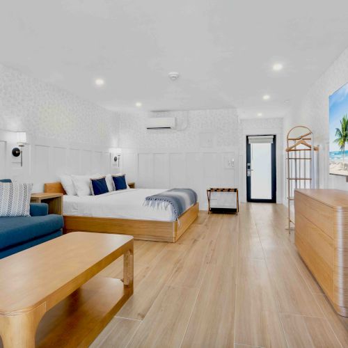 A bright, modern kitchen with light wood cabinets, white countertops, a central island, and a doorway leading to a dining/living area, open-plan.