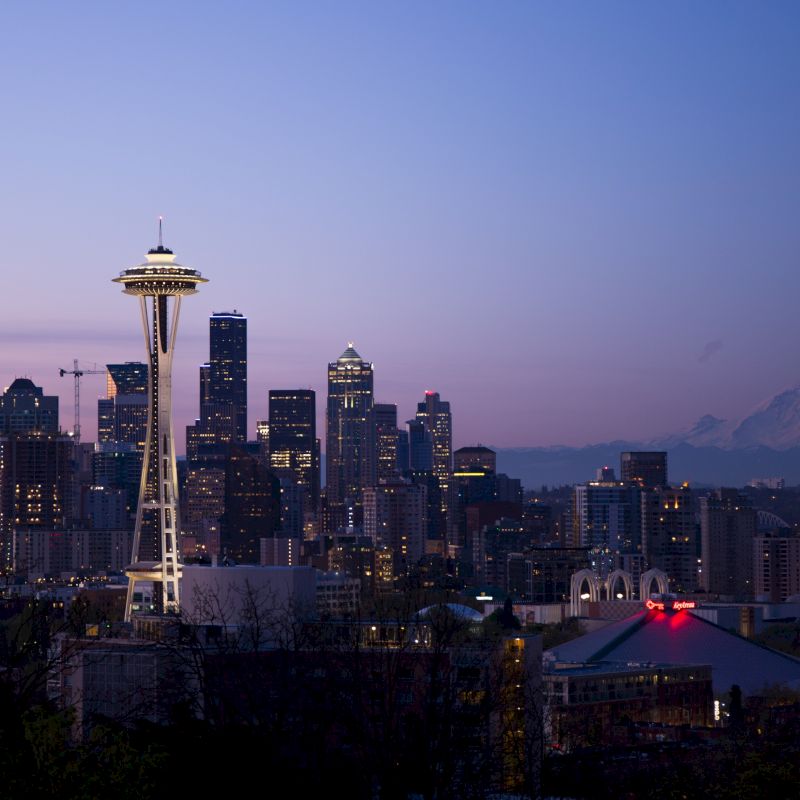 A twilight view of Seattle's skyline with the Space Needle and Mount Rainier in the background.